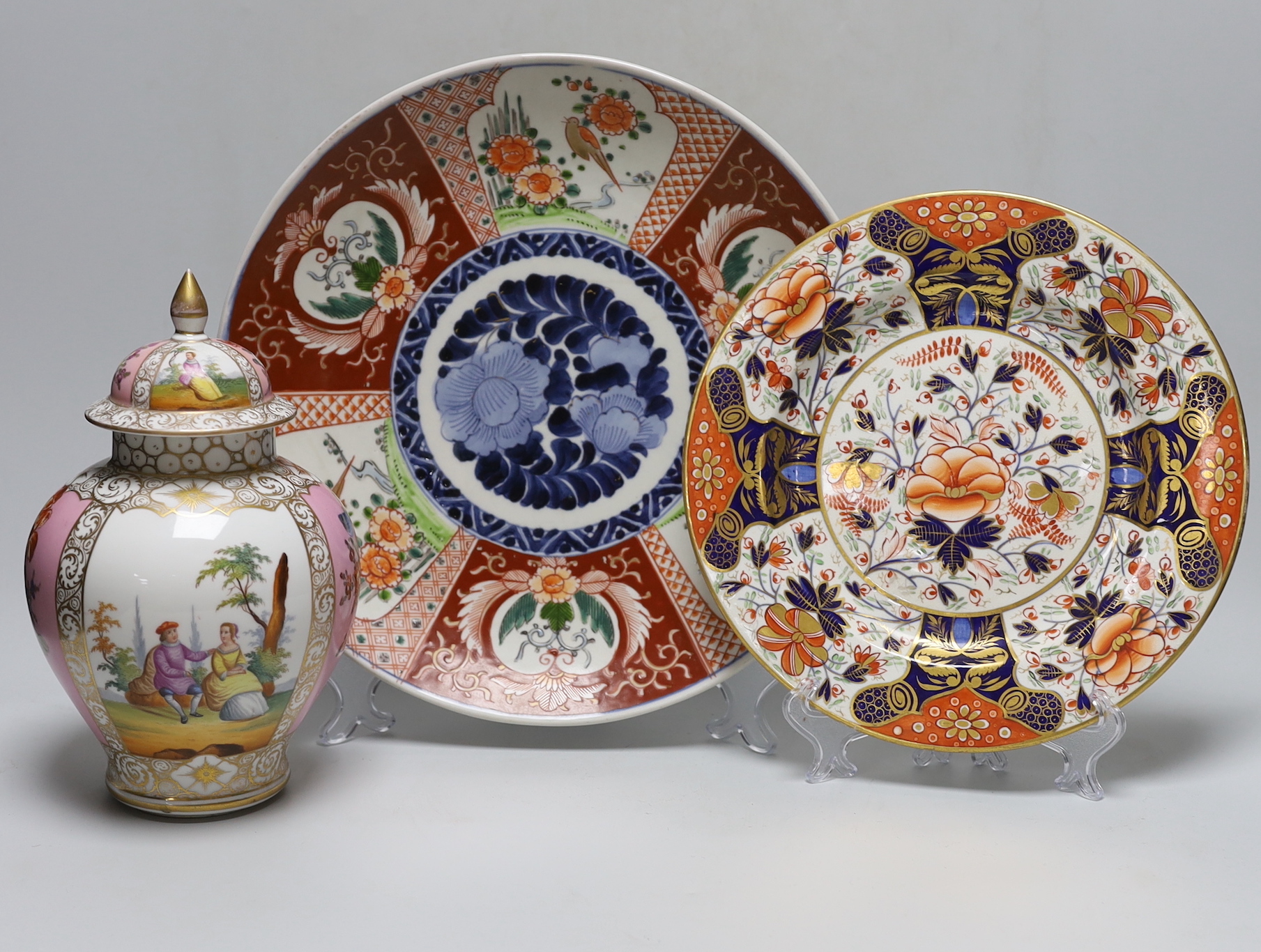 A Dresden pink ground jar and cover with gilt and floral decoration, 23cm tall, an Imari charger and a Royal Crown Derby plate